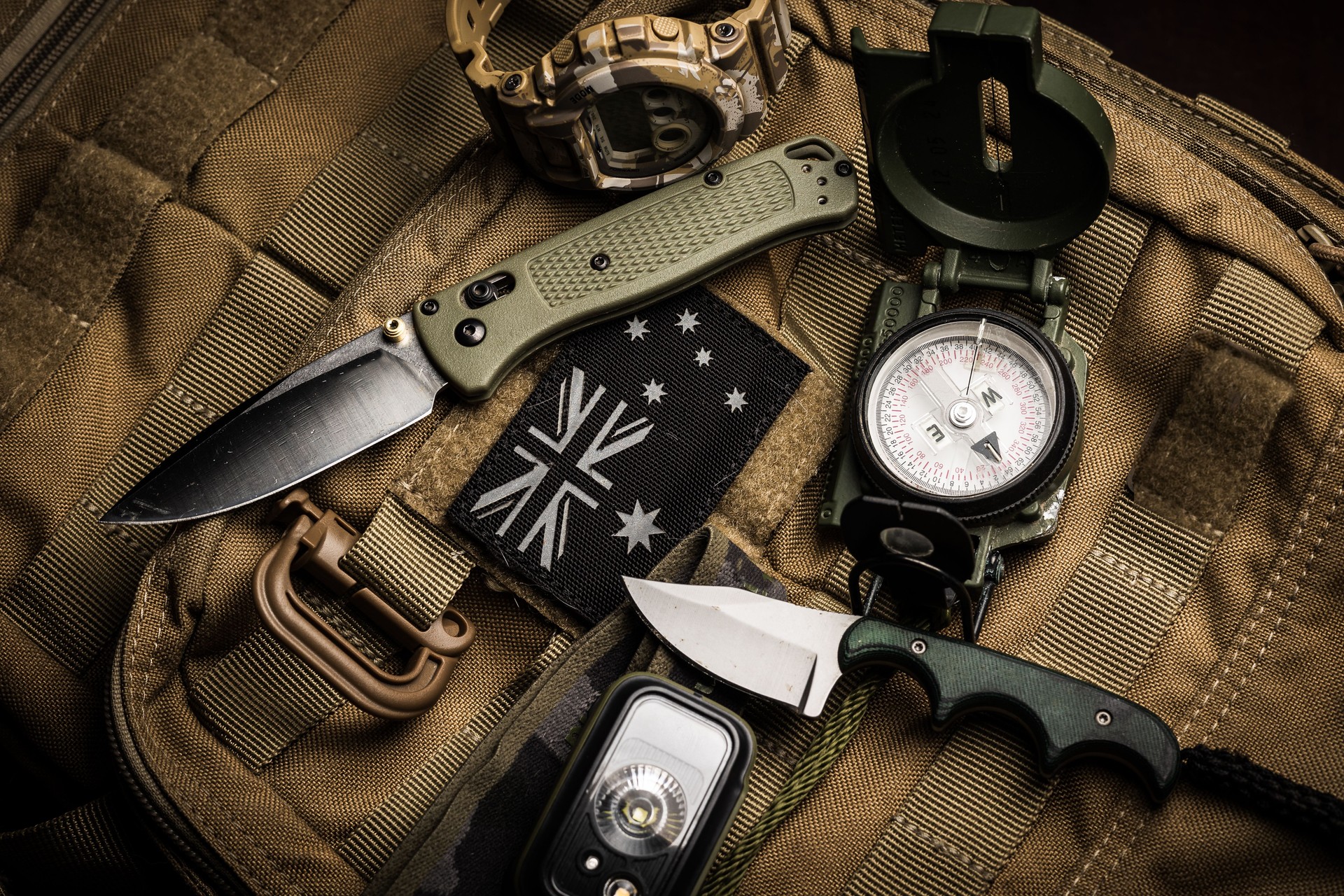 Flat lay tactical EDC and hiking gear on backpack