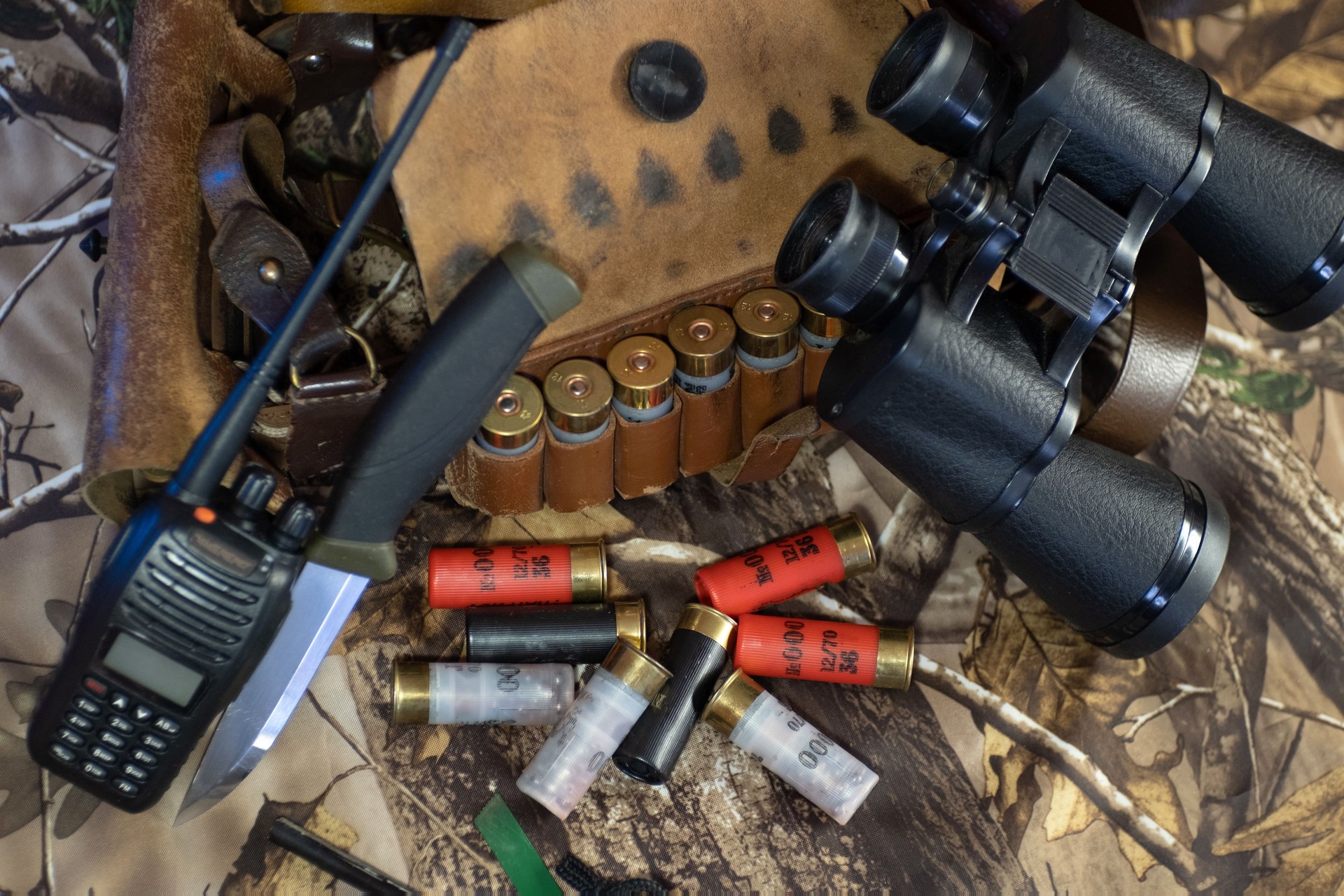 haunting equipment of shotgun cartridge belt, knife, binocular, and radio on the camouflage background